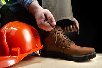 Construction worker lacing up boots